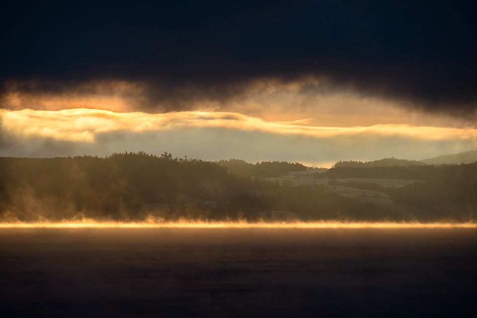 Sonnenreflexionen im Nebel auf der Wasseroberflaeche