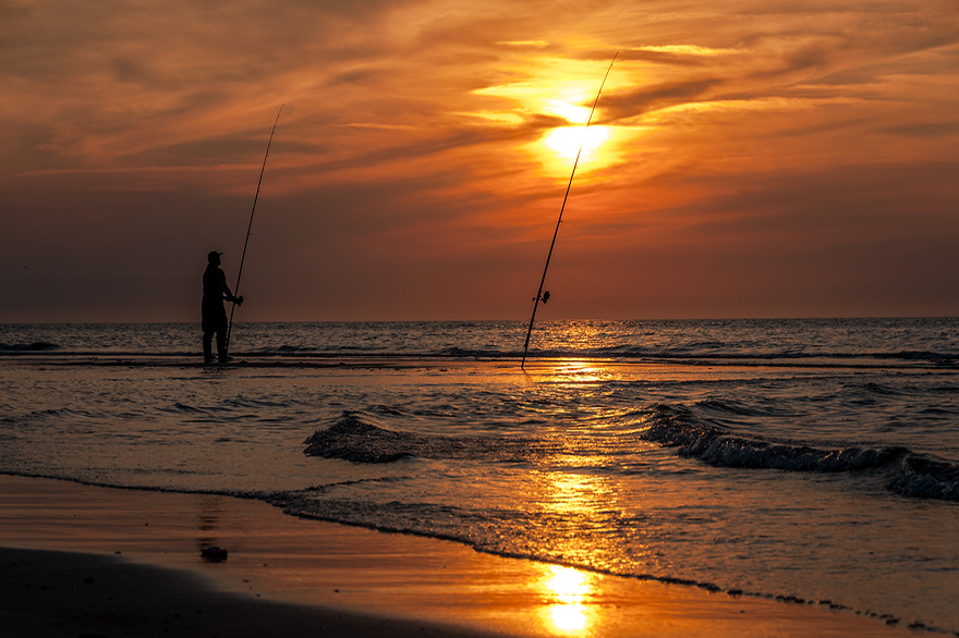 Angler im Sonnenuntergang am Strand 