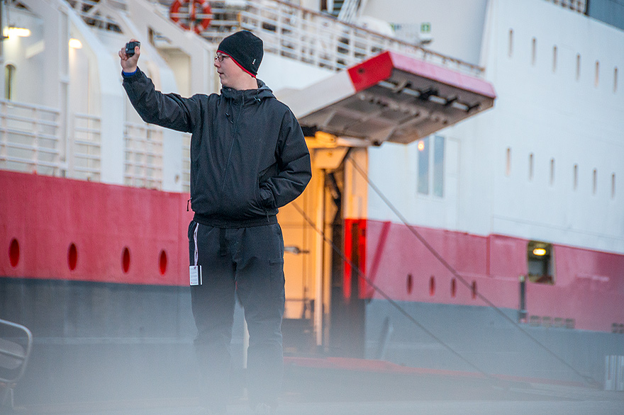 Gast auf der Vesteraelen macht ein Selfie vor dem Schiff im Hafen